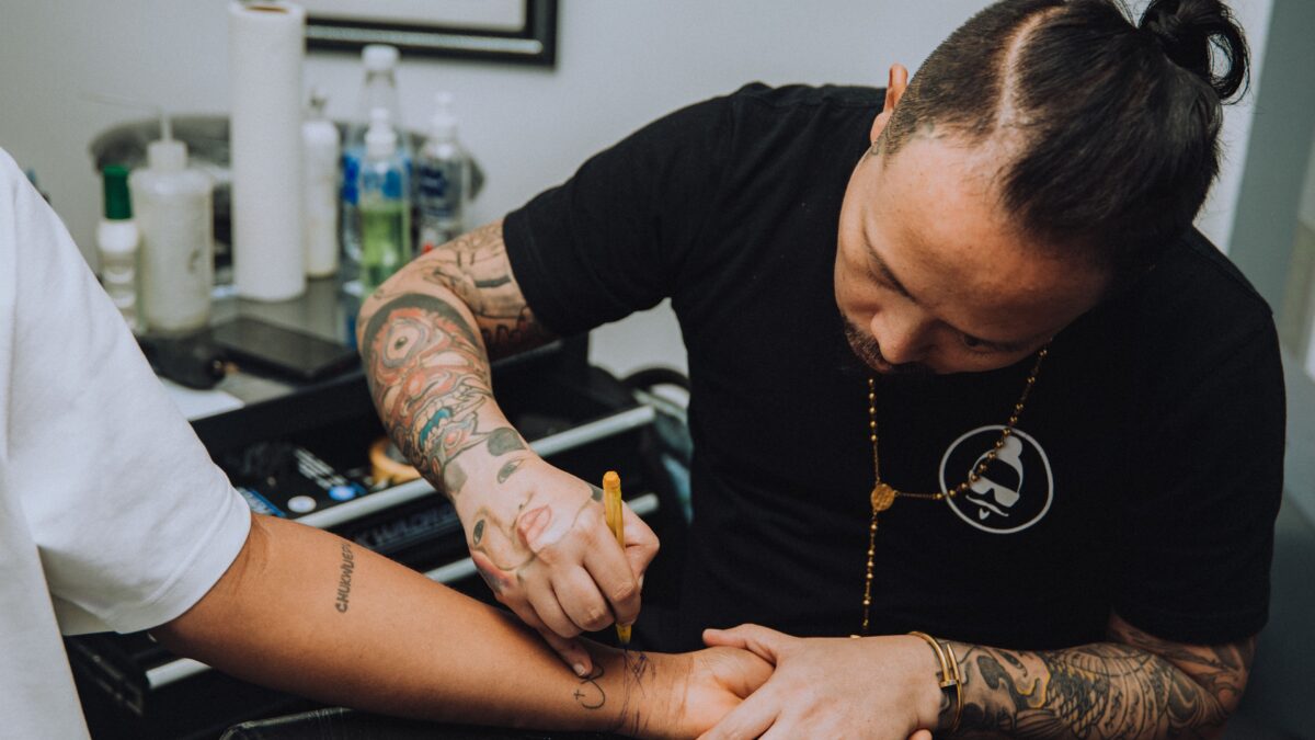 Tattoo artist drawing a design onto a client’s forearm